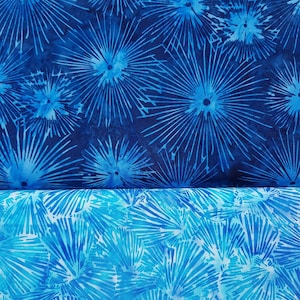 Könnte beinhalten: Zwei Stücke blauer Stoff mit einem weißen und blauen Blumenmuster. Der Stoff hat ein Batik-Design mit einem dunkelblauen Hintergrund und einem hellblauen Blumenmuster.