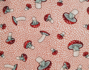 May include: A pink fabric with a repeating pattern of red and white mushrooms. The mushrooms have white stems and red caps with white spots.