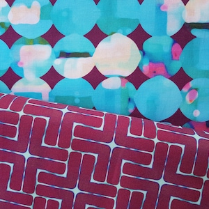 May include: Two fabric swatches, one with a pattern of teal blue circles on a burgundy background, and the other with a geometric pattern of burgundy rectangles on a white background.