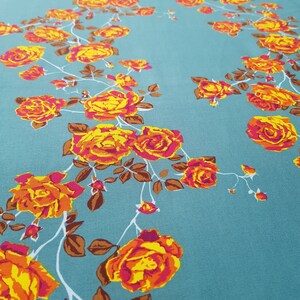 May include: Teal fabric with a floral pattern of orange and yellow roses with pink centers. The roses are arranged in a vine-like pattern.