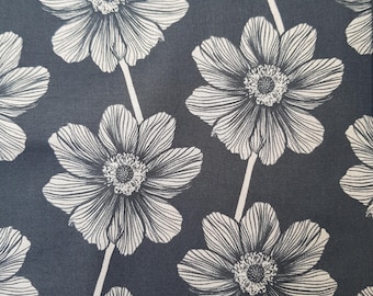 May include: A close-up of a fabric featuring a repeating floral design. Large, white stylized flowers with detailed petals are set against a dark grey background. The flowers are connected by thin, white stems, creating a visually appealing textile design.