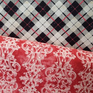 Könnte beinhalten: Zwei Stoffmuster, eines mit rotem Hintergrund und einem weißen Damastmuster und das andere mit einem schwarz-weißen Karomuster.