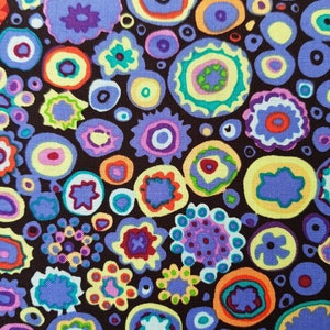 Op de afbeelding: Een paarse stof met een herhalend patroon van kleurrijke cirkels en abstracte vormen. De achtergrond is donkerbruin.