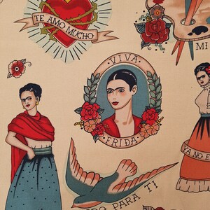 Op de afbeelding: Een kleurrijke stof met een herhalend patroon van Frida Kahlo ge&iuml;nspireerde tatoeages. De tatoeages omvatten een hart met doornen, een vogel, een palet, een roos en een portret van Frida Kahlo. De tekst op de stof is "Te Amo Mucho", "Viva Frida", "Todo Para Ti" en "Ya No Es", allemaal in het Spaans.