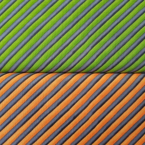 May include: A fabric with diagonal stripes in two colours. The top half of the fabric is green with dark grey stripes. The bottom half of the fabric is orange with dark grey stripes.