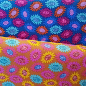 May include: Two fabric swatches with a repeating pattern of stylized sunflowers. The top swatch is a dark blue background with pink, red, and yellow flowers. The bottom swatch is a light brown background with pink, yellow, and blue flowers.