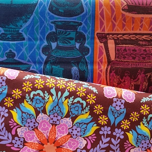May include: A close-up of fabric with a colorful floral pattern. The fabric is brown with yellow, blue, pink, and orange flowers. The fabric is folded over a second fabric with a pattern of blue and orange vases.