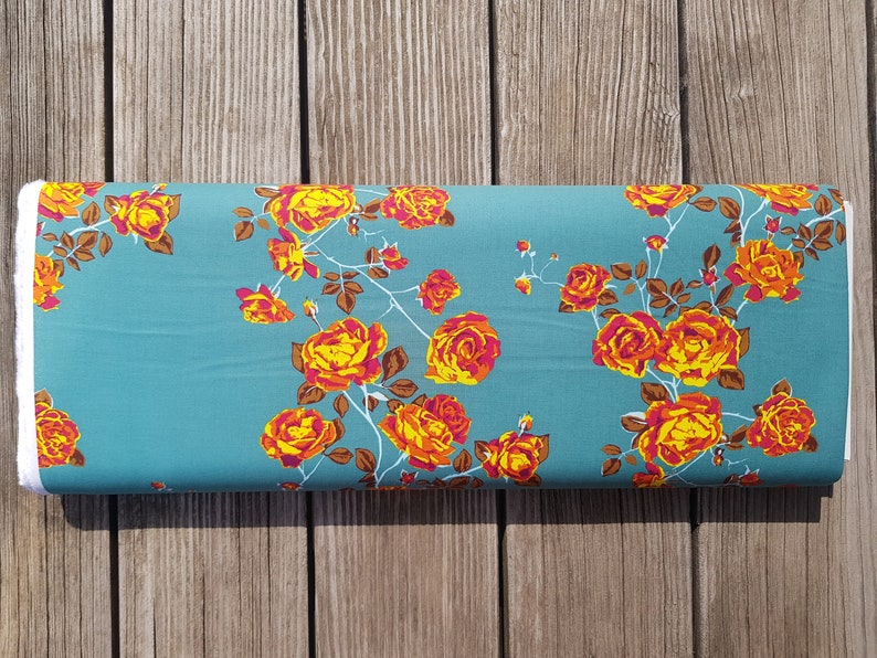 May include: Teal fabric with a floral pattern of orange and pink roses. The roses are arranged in a repeating pattern on the fabric.