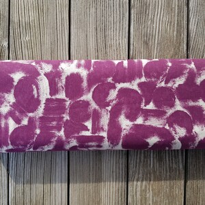 May include: A close-up of a purple fabric with a white abstract pattern. The fabric has the words "HARMONY" and "COTTON + SILK" printed on the edge.