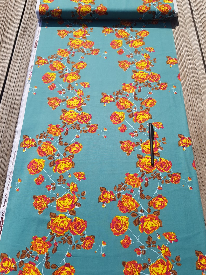 May include: Teal fabric with a repeating pattern of orange and yellow roses with brown stems and leaves. The fabric has the text "Love Always AM" printed on the side.
