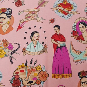 May include: Pink fabric featuring illustrations of Frida Kahlo, hearts, arrows, and text in Spanish. The design includes images of scissors, paint palettes, and doves, creating a vibrant and artistic pattern.