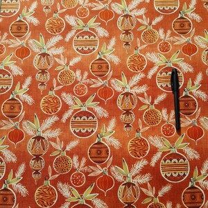 May include: Orange fabric with a repeating pattern of stylized Christmas ornaments. The ornaments are in shades of brown, orange, and white. The background is a textured orange.
