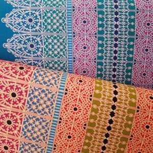 Puede incluir: Un primer plano de tela con un patrón repetitivo de formas geométricas y diseños intrincados. La tela es una mezcla de colores turquesa, rosa, verde y dorado.
