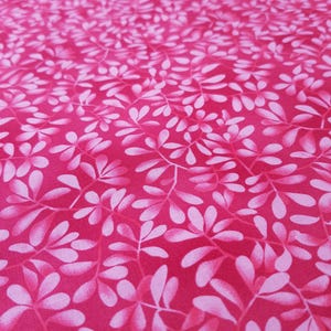 Könnte beinhalten: Nahaufnahme eines leuchtend pinkfarbenen Stoffes mit einem sich wiederholenden Muster aus weißen und hellrosa blattartigen Formen. Die Blätter sind dicht angeordnet und erzeugen einen strukturierten Effekt. Das Material ist wahrscheinlich Baumwolle oder ein ähnlicher Stoff.