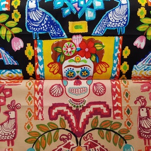 Può includere: Primo piano di due modelli di tessuto. Il tessuto superiore è nero con disegni colorati di uccelli e fiori. Il tessuto inferiore è beige con un disegno di teschio di zucchero e uccello. Entrambi i tessuti hanno un tema del Giorno dei Morti.