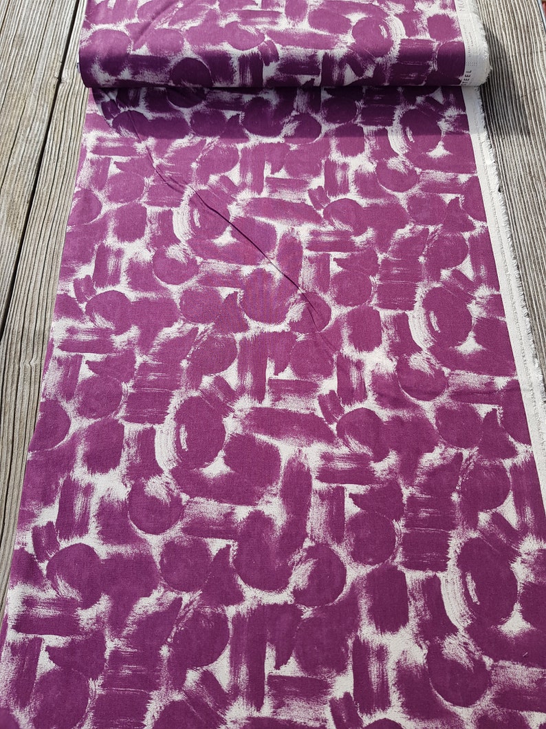 May include: Purple fabric with a white abstract brushstroke pattern. The fabric is folded in half and the pattern is visible on both sides.