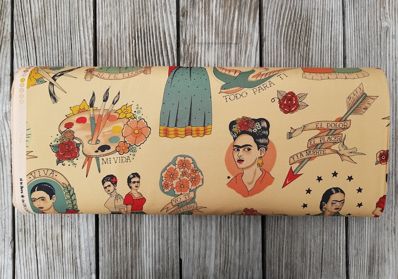 Op de afbeelding: Een beige stof met een herhalend patroon van Frida Kahlo ge&iuml;nspireerde illustraties. De illustraties omvatten een palet, bloemen, vogels en pijlen. De tekst "Mi Vida", "Viva", "Todo Para Ti", "Yo Te Quiero", "El Dolor El Placer Y La Muerte" is opgenomen in het patroon.