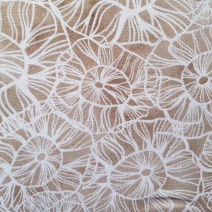 Könnte beinhalten: Weißes Blumenmuster auf einem beigefarbenen Stoffhintergrund. Das Muster besteht aus sich wiederholenden Kreisen mit komplizierten Linien.