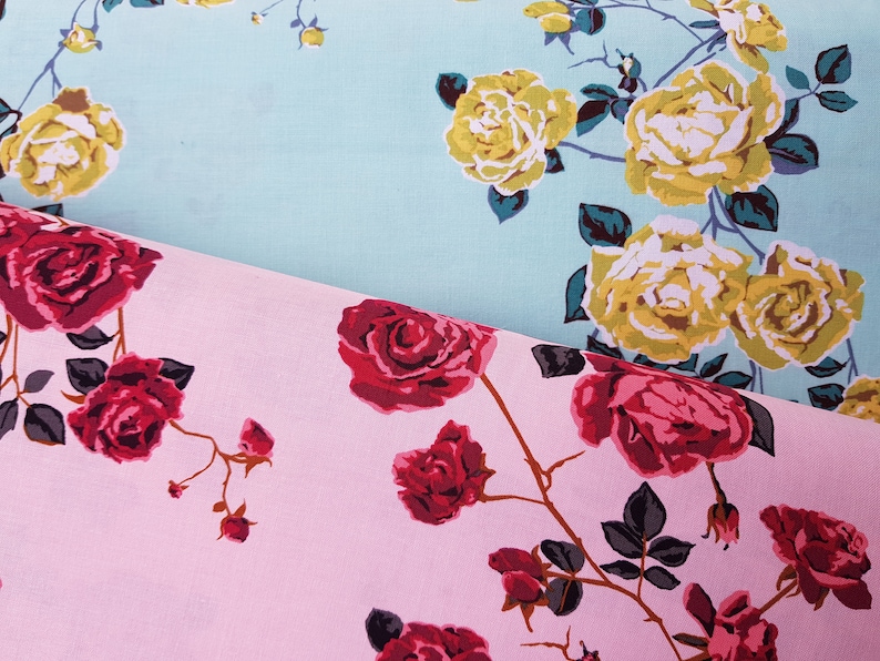 May include: Two fabric swatches with floral patterns. The top swatch is light blue with yellow roses. The bottom swatch is pink with red roses.