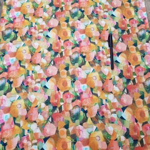 Puede incluir: Una tela con un estampado de flores abstractas en tonos naranja, rosa, amarillo y verde, realizado en estilo acuarela.
