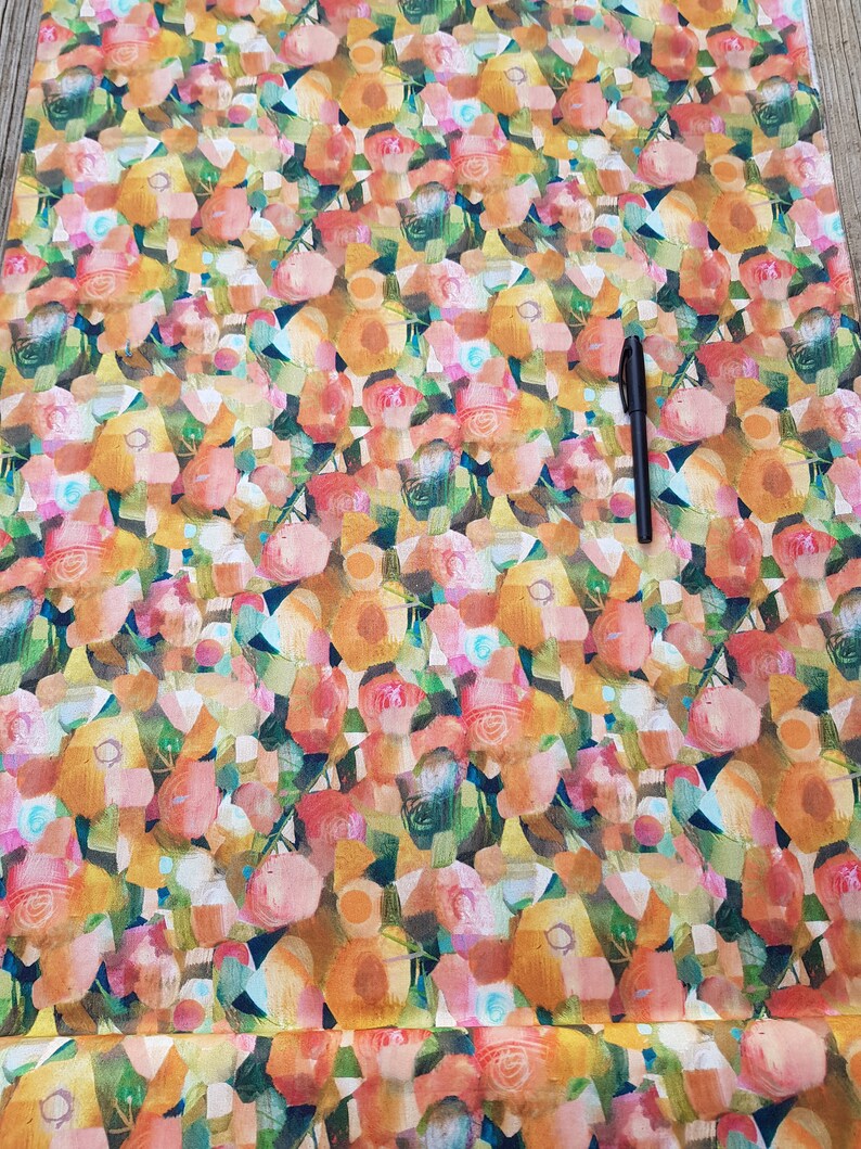 Puede incluir: Una tela con un estampado de flores abstractas en tonos naranja, rosa, amarillo y verde, realizado en estilo acuarela.