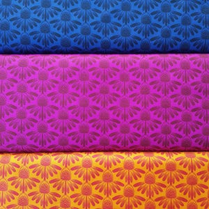 May include: Three fabric swatches in blue, magenta, and yellow, each with a repeating floral pattern. The flowers have a central cone shape with radiating petals. The blue and magenta fabrics have darker floral patterns, while the yellow fabric has a red floral pattern.