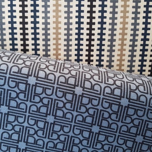 May include: Two fabric swatches with geometric patterns. The top swatch has a repeating pattern of black and blue lines on a white background. The bottom swatch has a repeating pattern of black squares and rectangles on a light blue background.