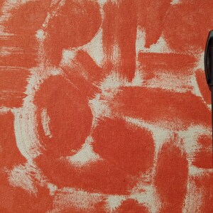 May include: A black pen on a textured orange and white surface. The surface has a pattern of white brushstrokes on an orange background.