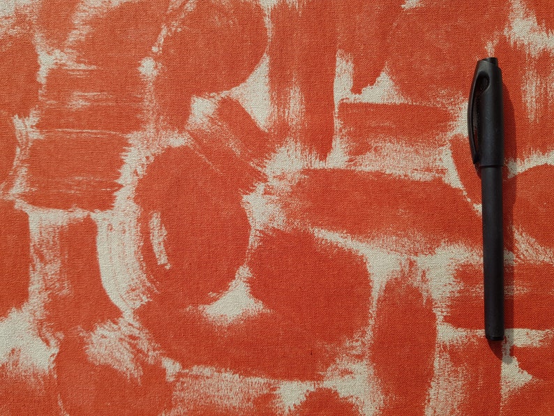 May include: A black pen on a textured orange and white surface. The surface has a pattern of white brushstrokes on an orange background.