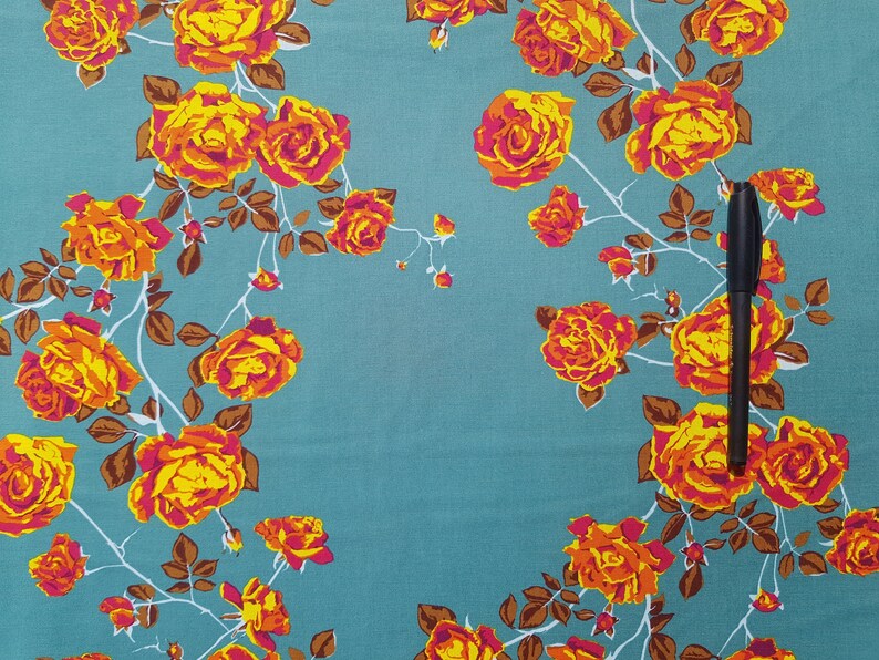 May include: Teal fabric with a floral pattern of orange and yellow roses. The fabric has a brown vine pattern.