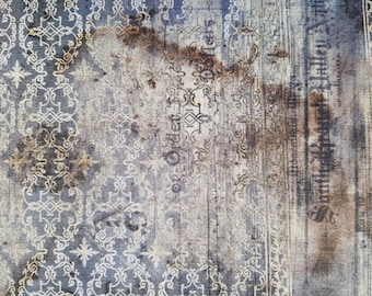 May include: Textured fabric with a vintage aesthetic. The design features ornate, cream-colored scrollwork and floral patterns against a faded blue and brown background. Vertical text is visible on the right side.