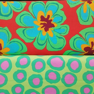 Può includere: Due pezzi di tessuto con un motivo floreale. Il pezzo superiore è rosso con grandi fiori blu, verdi e gialli. Il pezzo inferiore è verde con cerchi rosa.