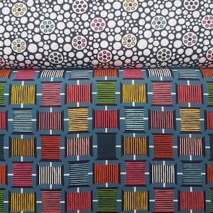 Może przedstawiać: Dwa próbniki tkaniny z geometrycznymi wzorami. Górny próbnik ma białe tło z czarnymi kółkami i kolorowymi koncentrycznymi kółkami wewnątrz każdego kółka. Dolny próbnik ma niebieskie tło z siatką kolorowych kwadratów z paskami.