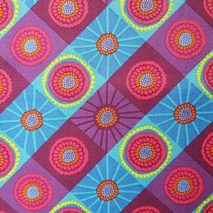 Könnte beinhalten: Ein farbenfroher Stoff mit einem sich wiederholenden Muster aus rosa, orange, gelben und blauen Blumen. Die Blumen sind in einem diagonalen Muster auf einem lila und blauen Hintergrund angeordnet.