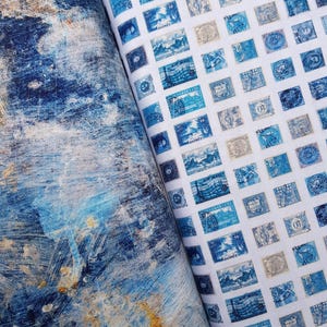 Może przedstawiać: Dwie rolki materiału. Jedna ma abstrakcyjny wzór w odcieniach niebieskiego, białego i beżowego. Druga przedstawia wzór niebieskich znaczków pocztowych na białym tle. Znaczki mają różne wzory i tekst.