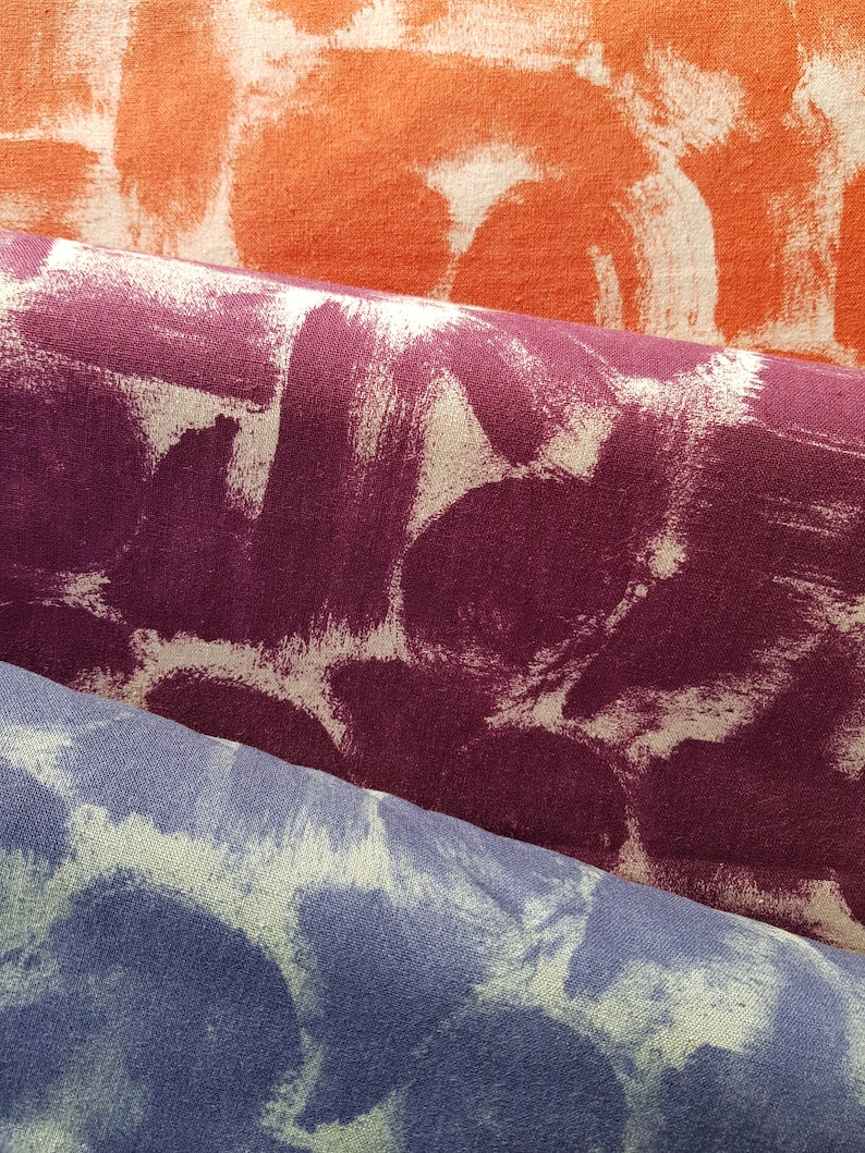 May include: Three fabric swatches with a white paint splatter design. The top swatch is orange, the middle swatch is purple, and the bottom swatch is blue.