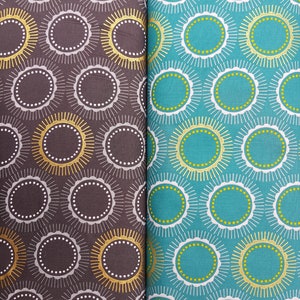 Peut inclure: Deux échantillons de tissu avec un motif répété de cercles blancs et dorés avec un motif de soleil sur un fond turquoise et marron.