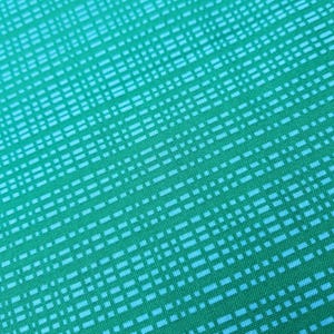 May include: A close-up of a turquoise fabric with a white grid pattern.