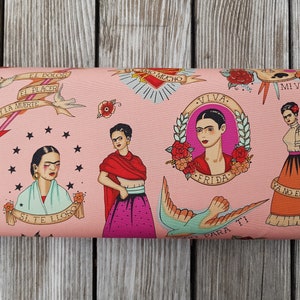 May include: Pink fabric roll featuring illustrations of Frida Kahlo with tattoo-style designs. The fabric includes portraits, floral elements, and phrases like "Viva Frida" and "Mi Vida".