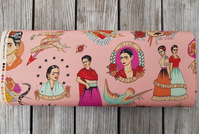 May include: Pink fabric roll featuring illustrations of Frida Kahlo with tattoo-style designs. The fabric includes portraits, floral elements, and phrases like "Viva Frida" and "Mi Vida".