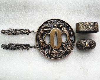 May include: A set of four gold-toned metal sword fittings, including a tsuba (sword guard) with a dragon design, a fuchi (collar) with a cloud design, a kashira (pommel cap) with a lion design, and two dragon-shaped seppa (spacer).