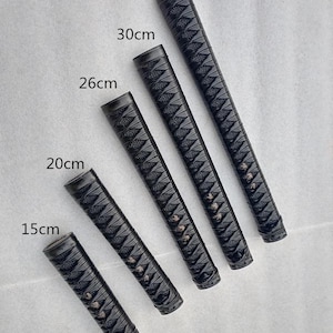 Może przedstawiać: Pięć czarnych rękojeści do katany o różnych długościach, od 15 cm do 35 cm. Każda rękojeść ma teksturowany, diamentowy wzór dla lepszego chwytu. Rękojeści są ułożone pod kątem na jasnym tle.