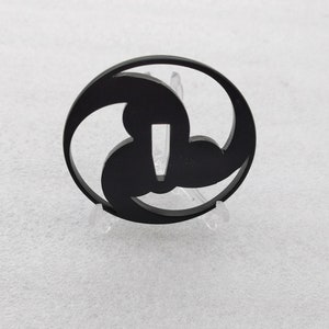 Peut inclure: Un tsuba en métal noir, une garde décorative pour un sabre japonais, avec un motif à trois lobes.