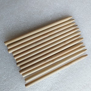 Puede incluir: Un paquete de 15 pinchos de madera natural, afilados en un extremo. Los pinchos están dispuestos en una pila ordenada, con los extremos puntiagudos orientados en la misma dirección.