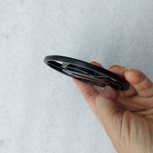 Puede incluir: Bobina de detector de metales negra de forma circular con un diseño estampado.