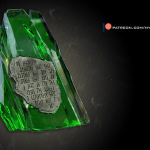 May include: A green crystal shard with a piece of paper inside. The paper has a series of symbols written on it.