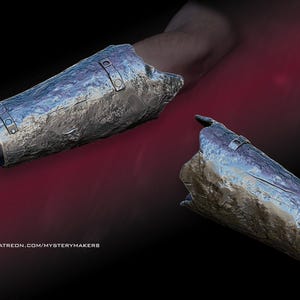 May include: Two silver metal arm guards, one is on a person's arm, the other is lying on a red surface. The arm guards are damaged and have a rough, textured surface.
