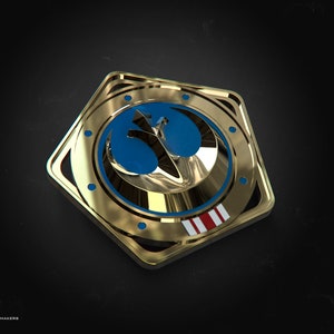 May include: A gold-colored, pentagon-shaped emblem with a blue and gold design. The emblem features a stylized bird symbol within a blue circle, with a red, white, and blue stripe detail. The emblem is set against a dark background.