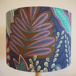 May include: A lampshade with a colourful floral pattern. The pattern features pink, green, blue and red leaves on a dark blue background.