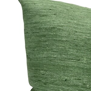Puede incluir: Una almohada verde con una tela texturizada. La almohada est&aacute; hecha de un material tejido con un brillo sutil.